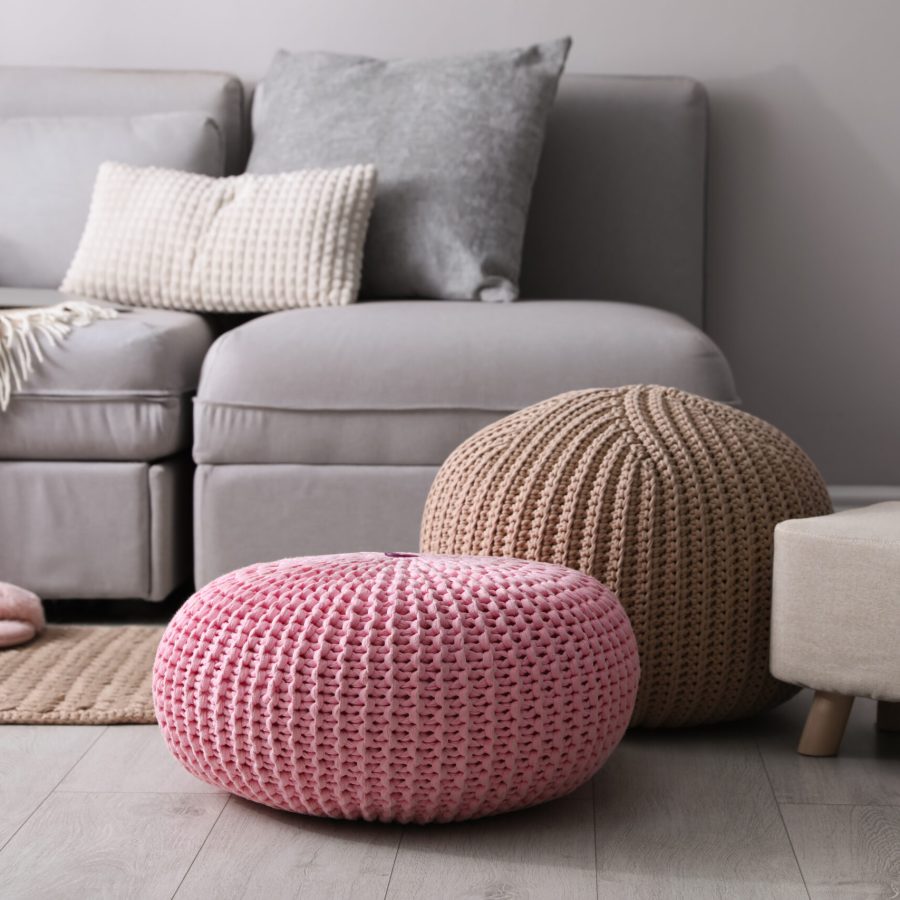 Stylish poufs and ottoman near sofa in living room. Interior element