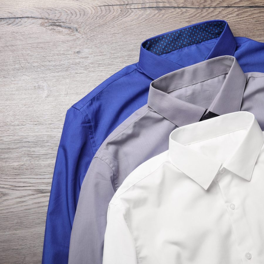 Stylish shirts on wooden table, flat lay. Dry-cleaning service