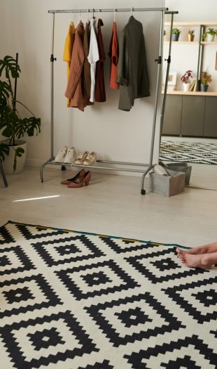 Serious young woman in cardigan sitting on bed and looking with sad around at home self-isolation during coronavirus
